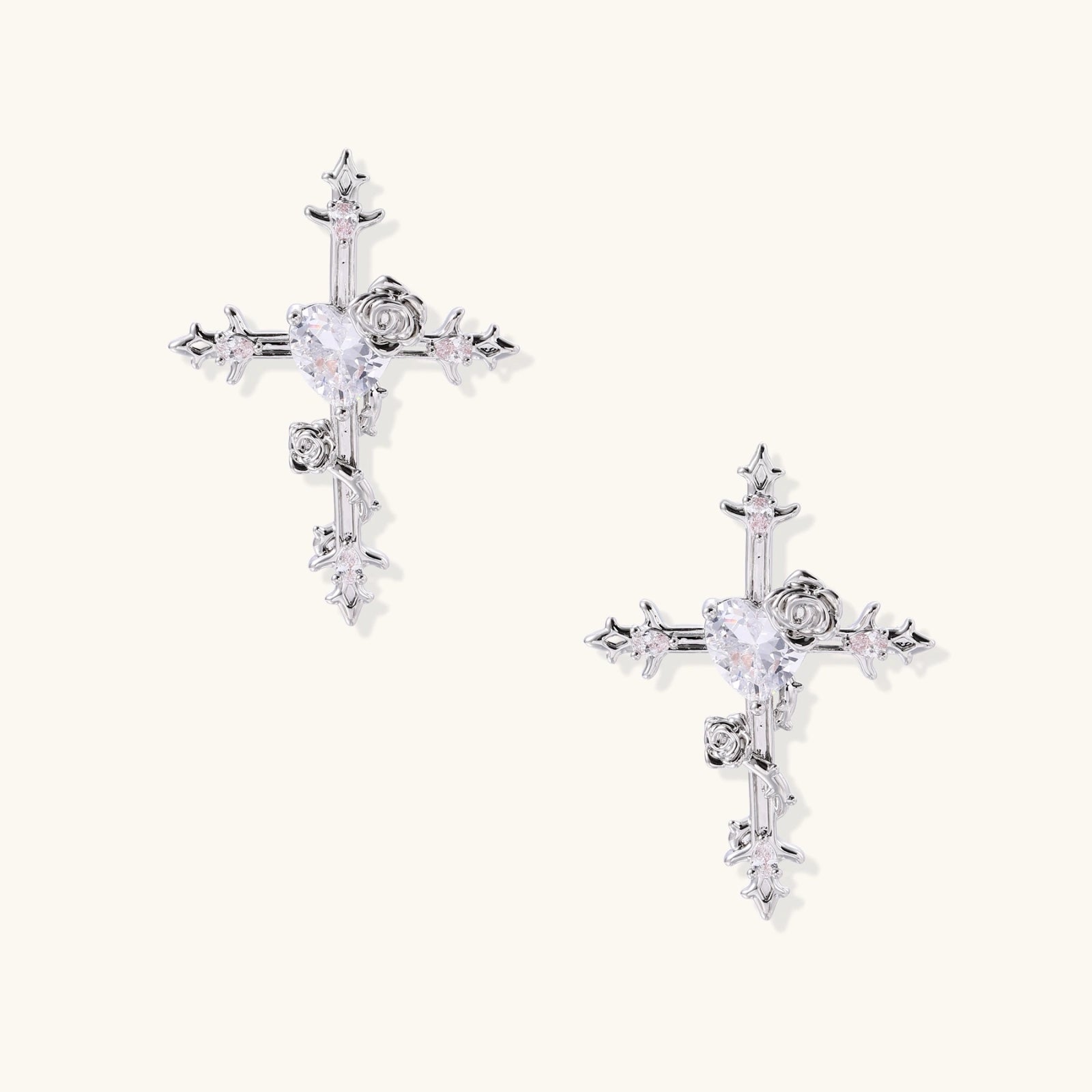 Ornate gold-plated cross earrings with zirconia stones and rose details on neutral background.