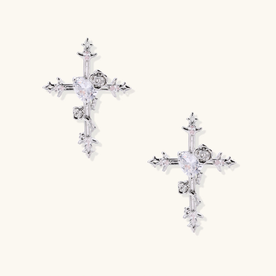Ornate gold-plated cross earrings with zirconia stones and rose details on neutral background.